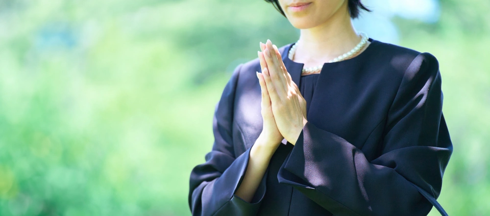 手を合わせている喪服の女性イメージ画像